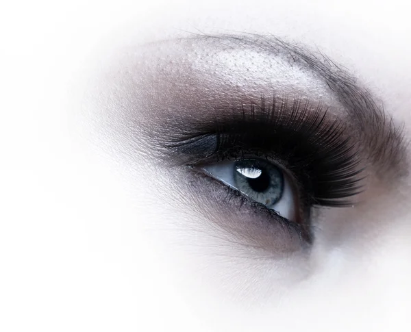 Human eye with eyelashes over white background