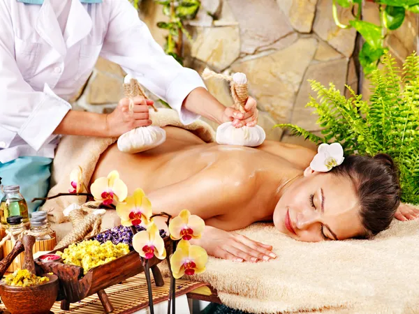 Woman getting thai herbal compress massage.