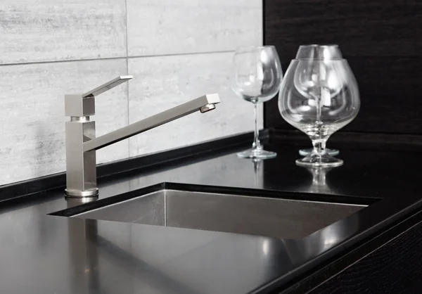 Modern kitchen sink with metal tap and black marble
