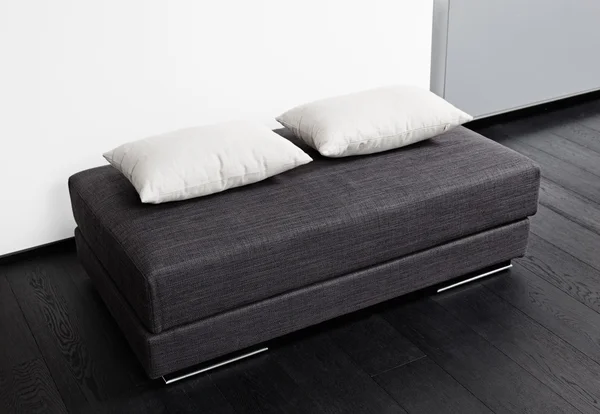 Dark gray padded stool with white pillow, interior detail