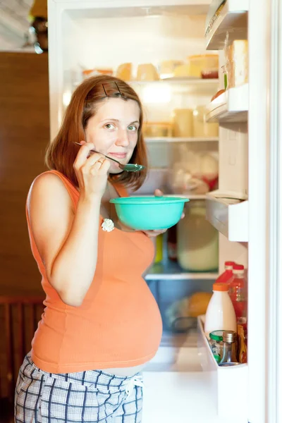 Pregnant woman eats from refrigerator