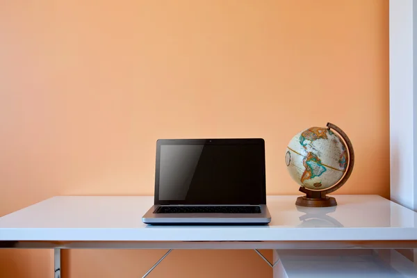 Students desk with globe and laptop
