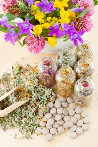Different healing herbs in glass bottles, flowers bouquet in mort