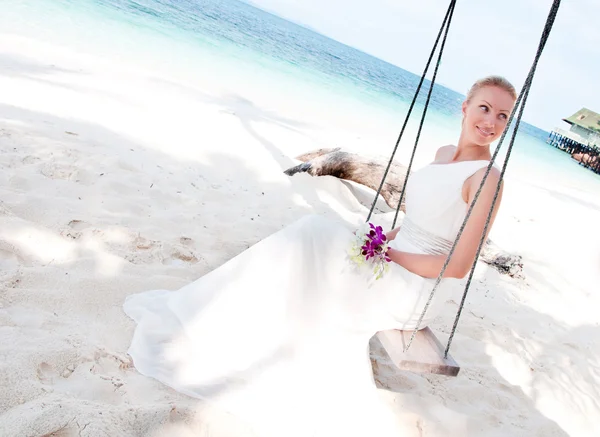 Beautiful bride swinging on tropical sea side background