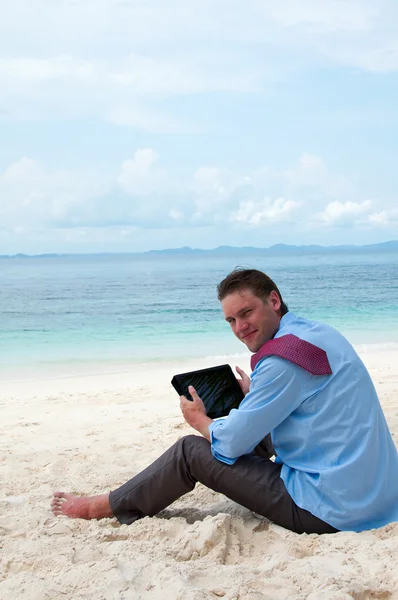 Business man sitting and working on the beach with tablet comput