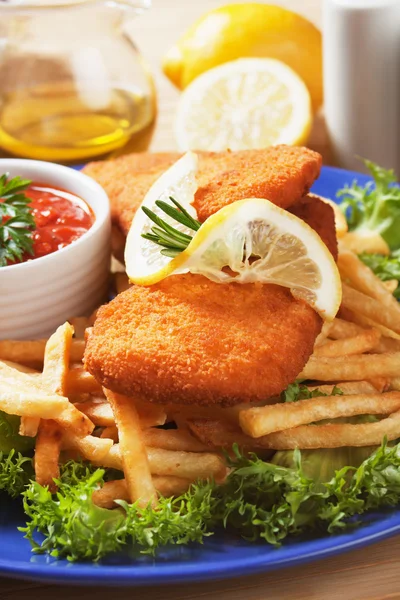 Breaded fish steaks with french fries, lemon and lettuce