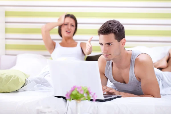 Woman screaming at man while he works on laptop