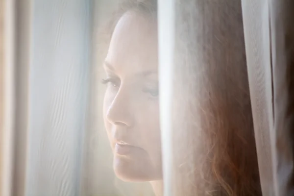 Sad woman looking through the window