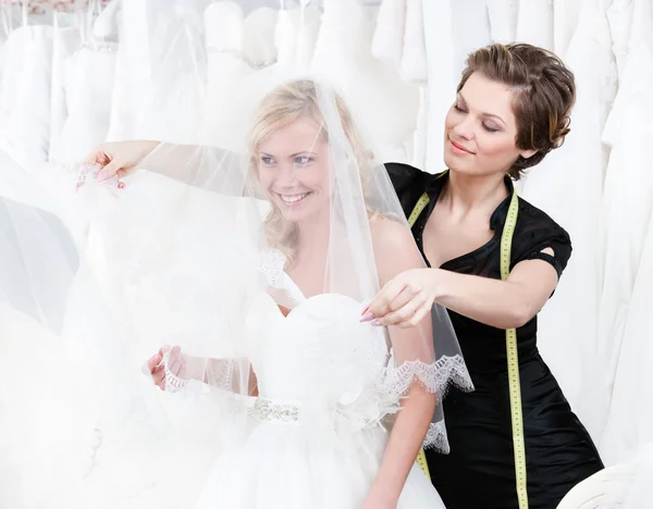 Shop assistant sets the veil of the bride