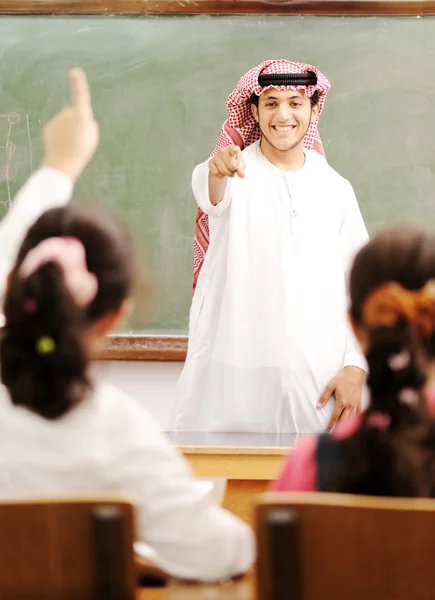 Arabic Muslim teacher in classroom with children. Competition an