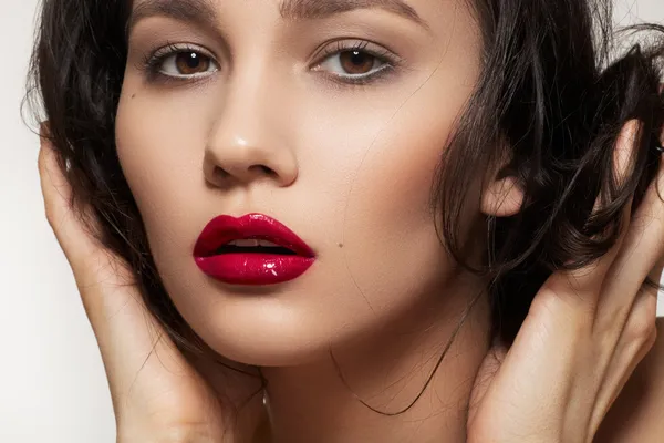 Close-up portrait of sexy caucasian young woman model with glamour dark red gloss lips make-up and purity complexion, beautiful romantic hairstyle. Perfect clean skin