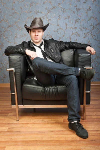 Young cowboy sitting in leather chair in the interior