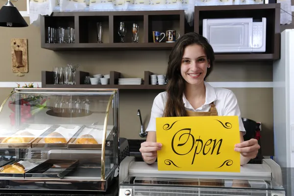 happy owner of a cafe showing open sign