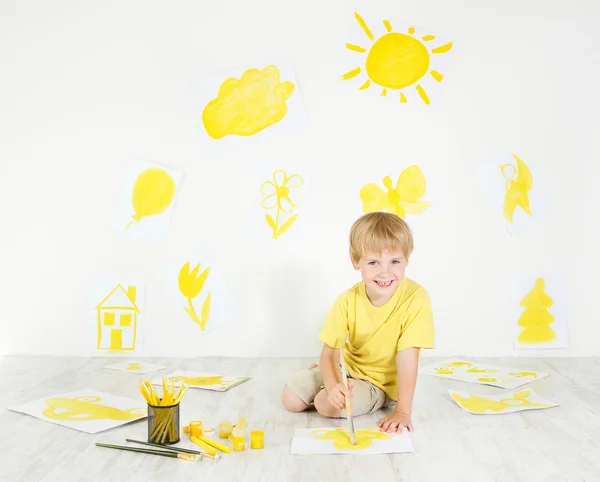 Happy child drawing with yellow color brush. Creativity concept.