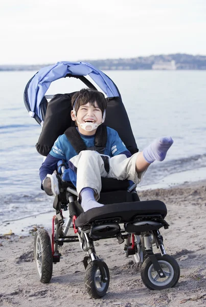 Happy disabled boy in wheelchair on the beach
