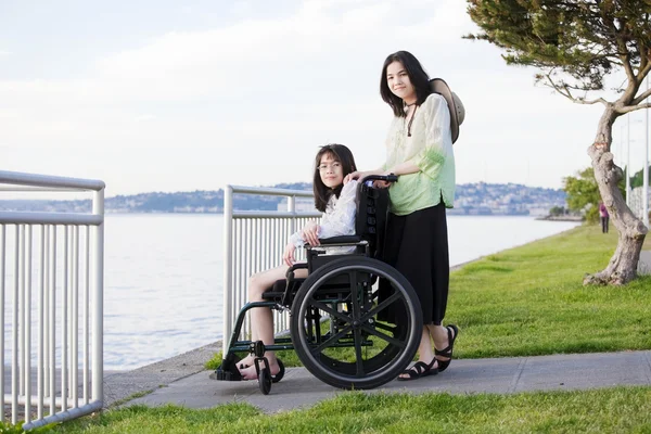 Taking care of sister in wheelchair by beach