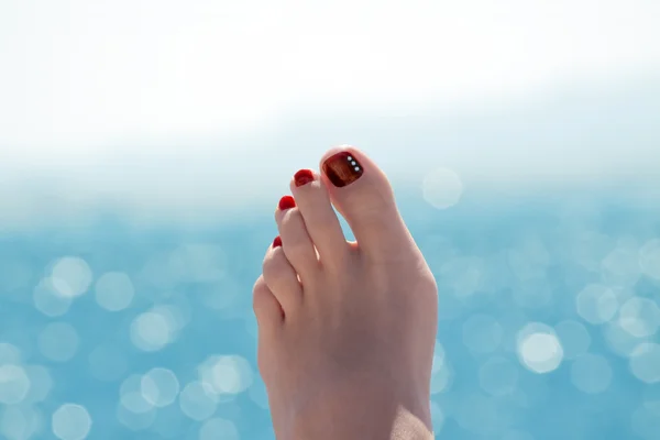 Female foot over blue ocean on sunny day