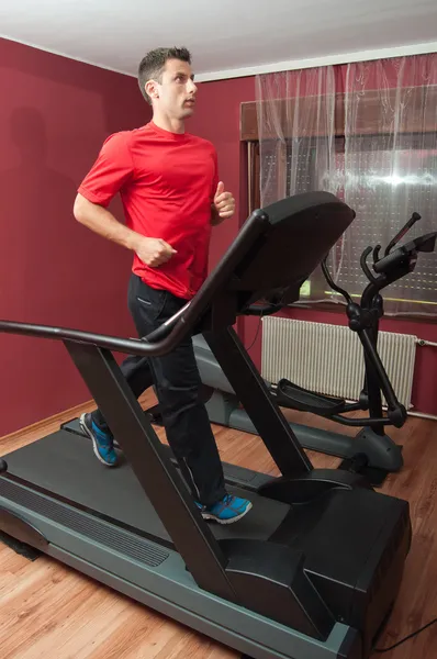 Young handsome man running on treadmill in home made gym