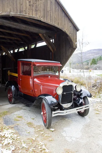 Old car at covered wooden bridge, Vermont, USA