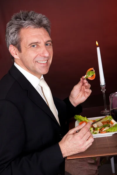 Mature man eating salad in restaurant