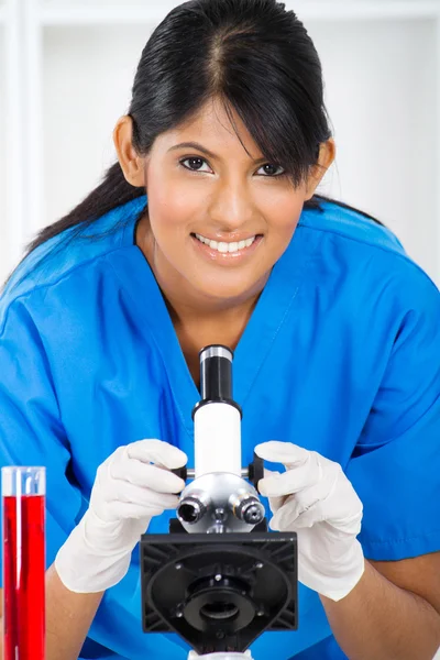 Young lab technician using microscope