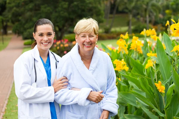 Caring doctor taking senior patient outdoors for some fresh air