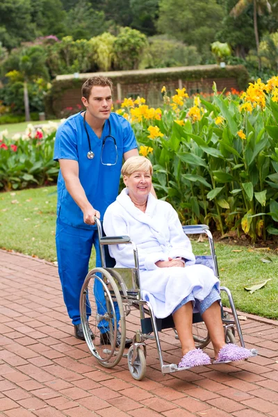 Male medical doctor pushing senior patient on wheelchair