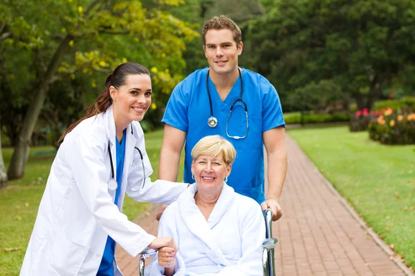Caring medical doctor, nurse and senior patient outdoors