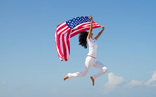 Young active woman with american flag and jumping