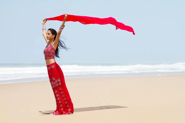 Indian woman holding sari on windy beach
