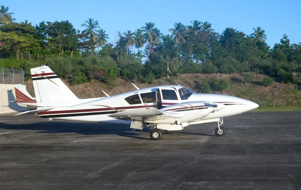 A small plane on the runway of tropical airfield