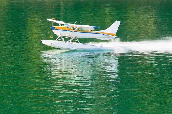 Aircraft seaplane taking off on calm water of lake