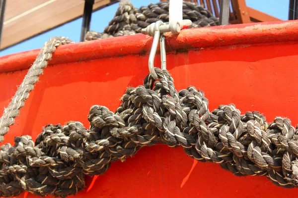 Close-up of an old frayed boat rope, on a red boat