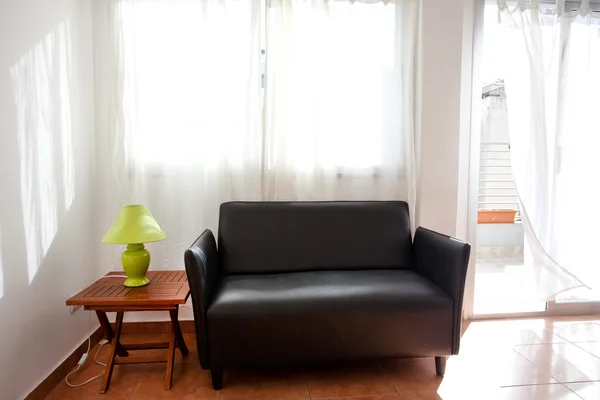 Black sofa and a lamp on the bedside table on a background of cu