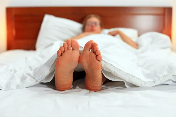 Young caucasian woman lying down in bed, feet in focus