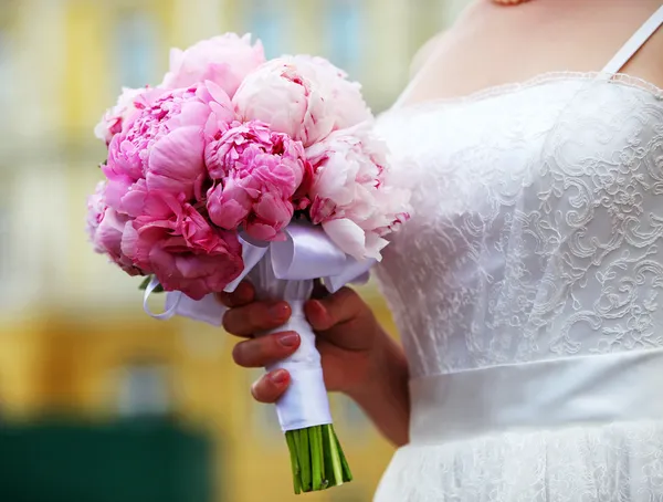 Closeup view of a bride holding bouquet of peonies