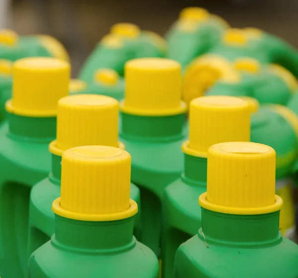 Rows of bright green plastic bottles with yellow caps