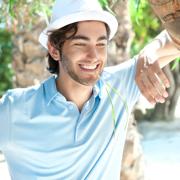 Young man wearing hat and casual clothes in sunny day. Leaning o