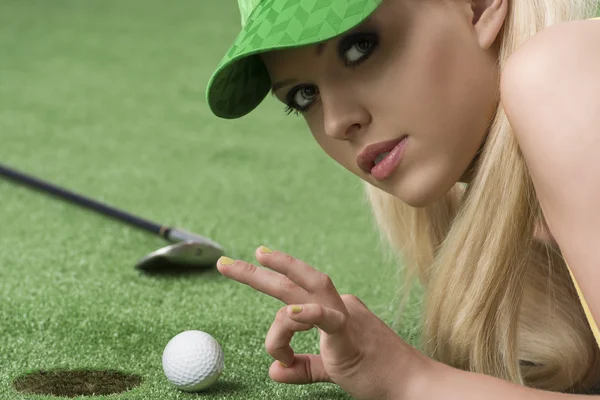 Girl's playing with golf ball looks in to the lens