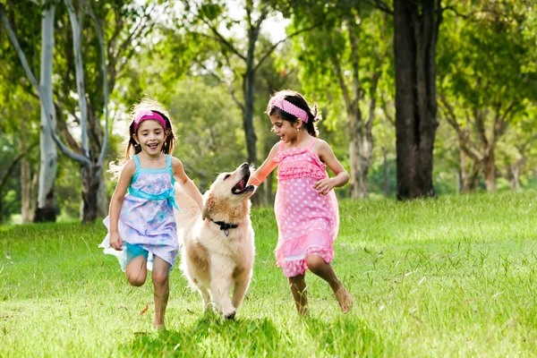 Two young girls running with golden retriever