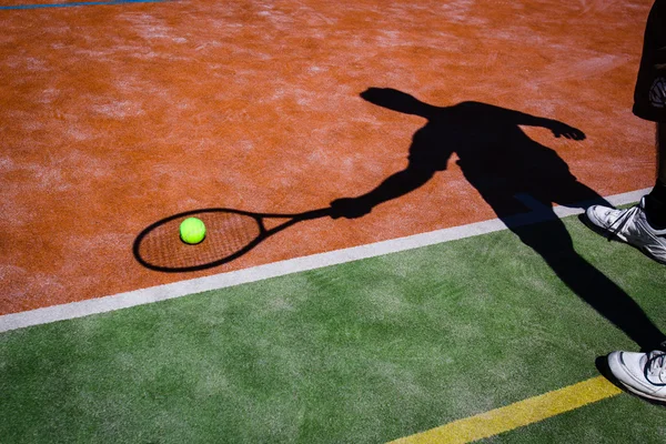 Shadow of a tennis player in action on a tennis court