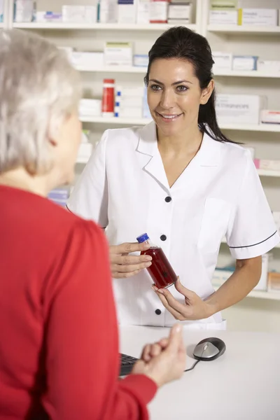 American pharmacist dispensing to senior woman