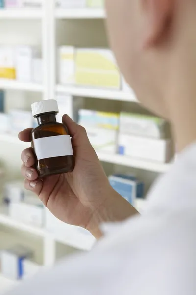 Pharmacist holding prescription pill bottle