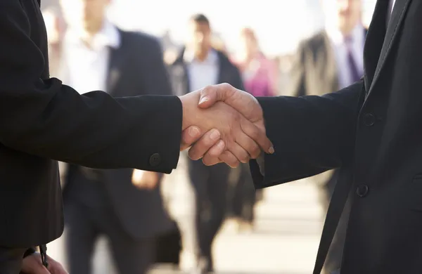 Businessman and business woman shaking hands in street