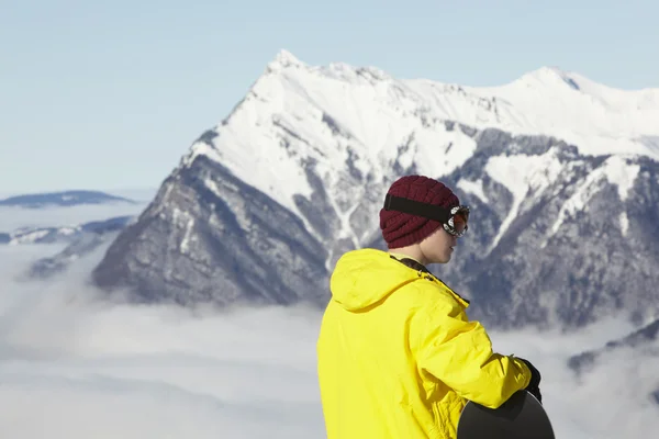 Teenage Snowboarder Admiring Mountain View Whilst On Ski Holiday