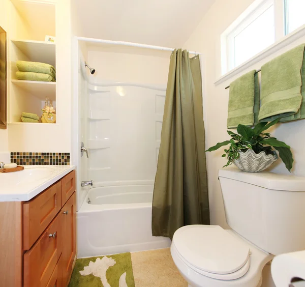 White and green bathroom with tub and cabinet.