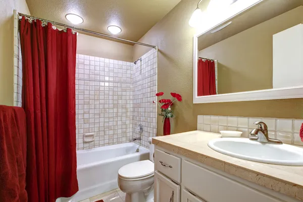 Elegant beige and red bathroom with tub and sink.