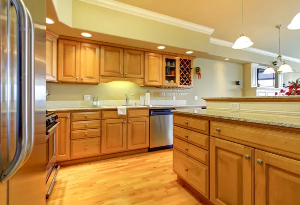 Golden wood kitchen with granite and stainless steal.