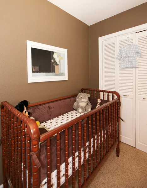 Cherry wood baby crib in nursery interior.