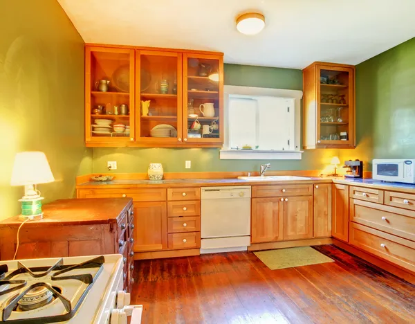 Green kitchen with wood cabinets and hardwood floor.